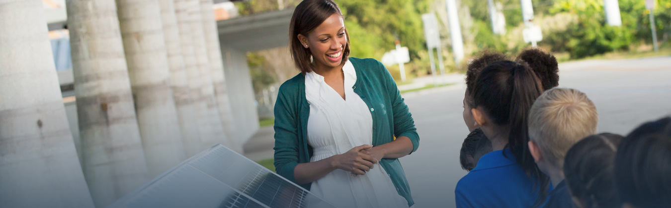 Woman educating a group of children about solar panels